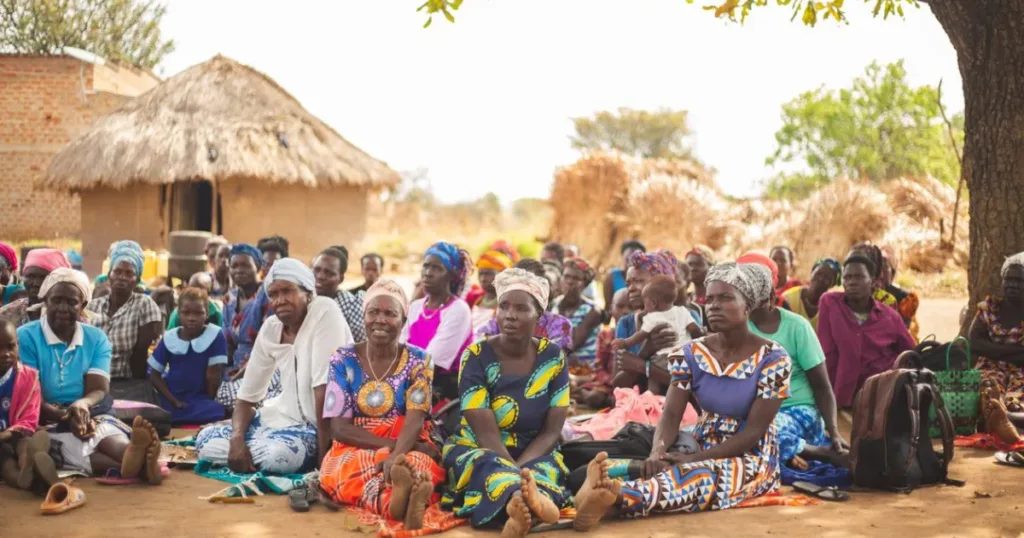 Group of people gathered together in an African village, representing a community savings group
