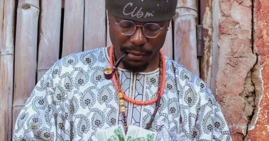 African man in traditional attire counting cash, representing choosing the best bank account for salary earners in Nigeria