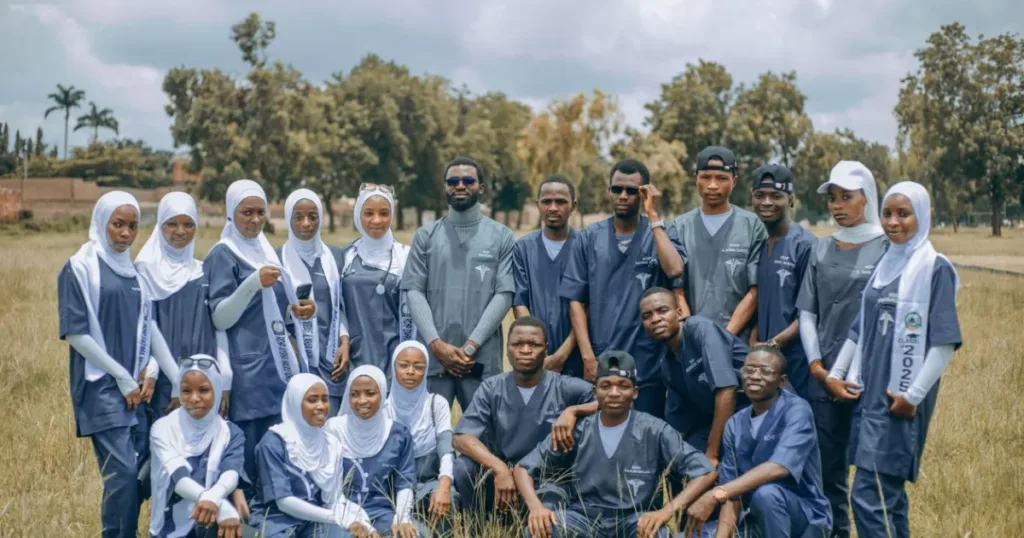 A group of Nigerian university students in matching uniforms posing together outdoors