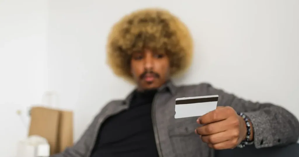 A young Nigerian man holding a bank card while making a purchase on his smartphone