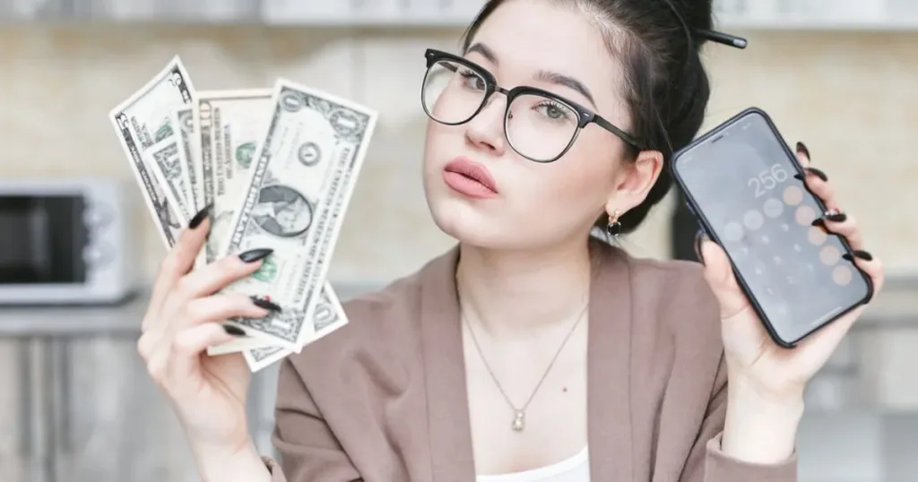 Hand holding cash and a smartphone, representing a ranking of the best financial tools for salary earners and students