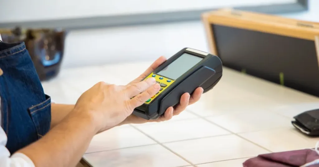 Close-up of hands processing a card payment on a POS machine