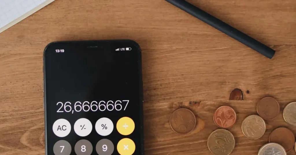 Top view of a smartphone calculator, coins and notebook on a table, representing a wallets and banks ranking comparison