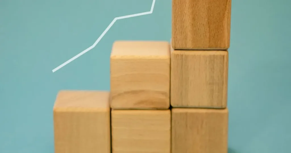Wooden blocks forming an ascending staircase with an upward arrow, symbolizing a roadmap to progress