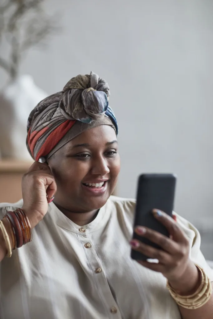 Woman smiling while using her smartphone at home