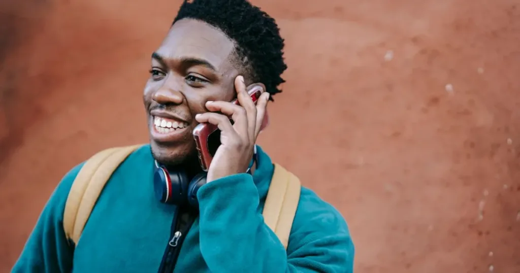 Cheerful young man talking on his phone outdoors on a city street