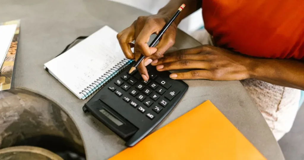 Woman using a calculator and notepad to budget her monthly salary