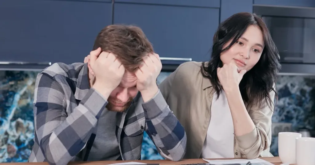 Worried couple reviewing financial documents at a kitchen table before borrowing