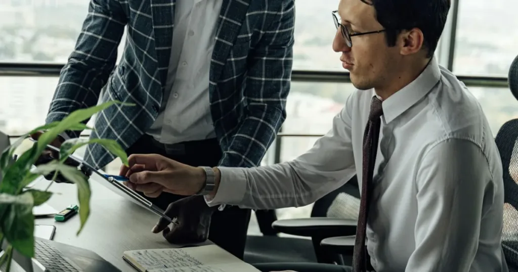 Two professionals discussing financial paperwork in a modern office, representing guidance on how credit bureaus work.