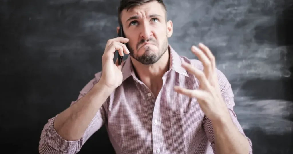 Stressed man talking on his smartphone indoors, wary of a suspicious loan call