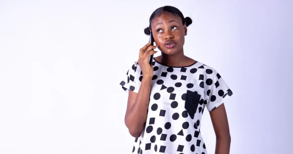 Thoughtful woman on a phone call, weighing a FairMoney loan app decision