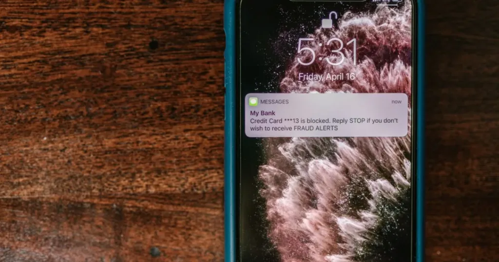 Smartphone displaying a fraud alert notification message on a wooden table