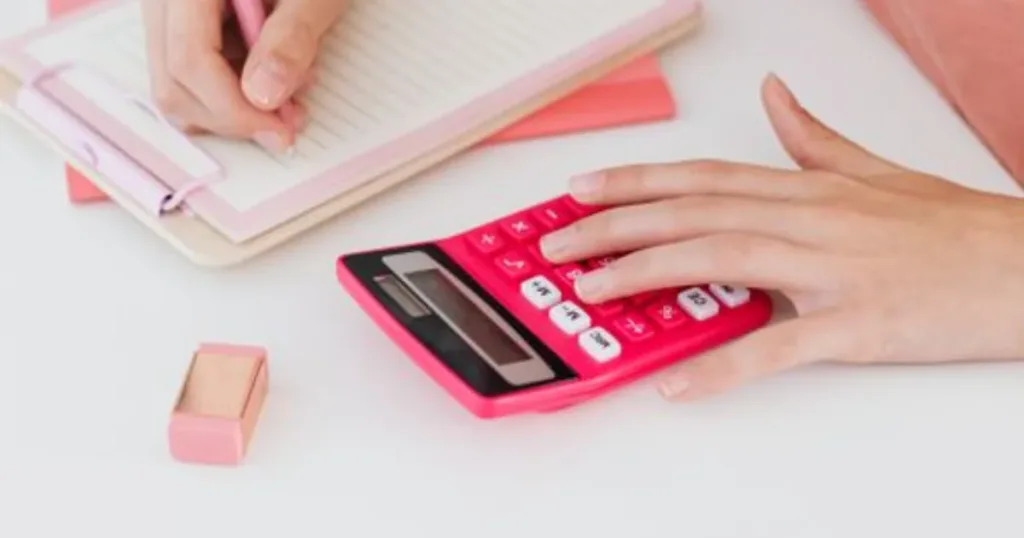 Woman using a calculator and notepad to budget her finances