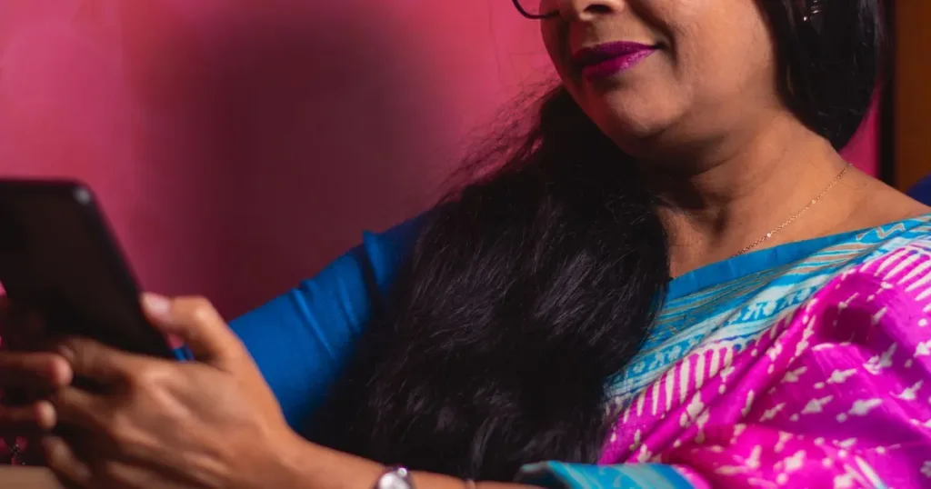 Indian woman in traditional attire using a smartphone at home to manage finances