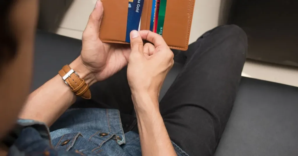 Man holding a wallet with several bank cards