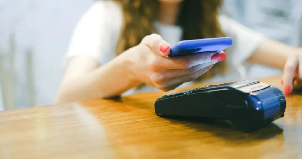 A woman processes a contactless payment using her smartphone