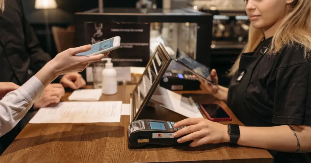 Customer using mobile phone for contactless payment at a coffee shop