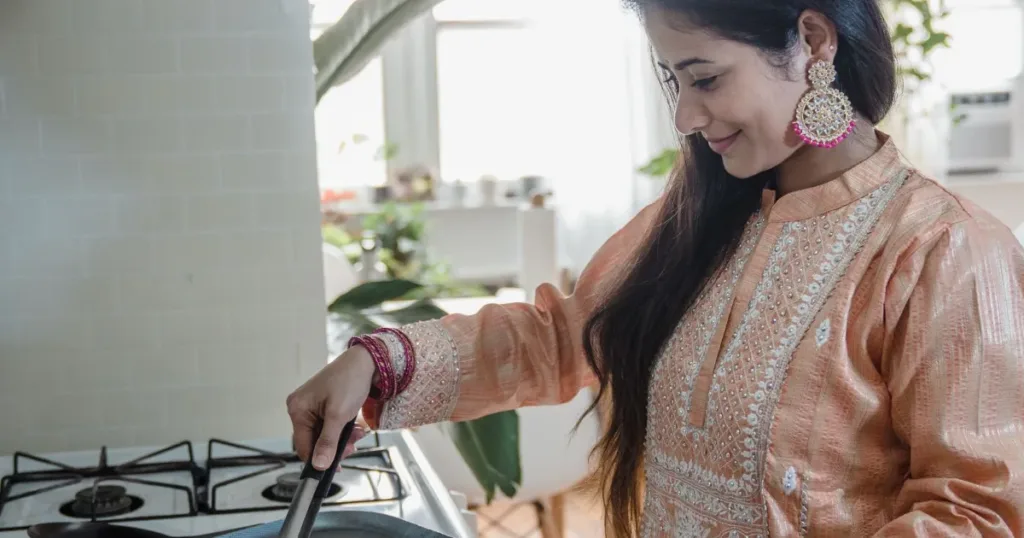 Indian homemaker smiling while cooking in her kitchen