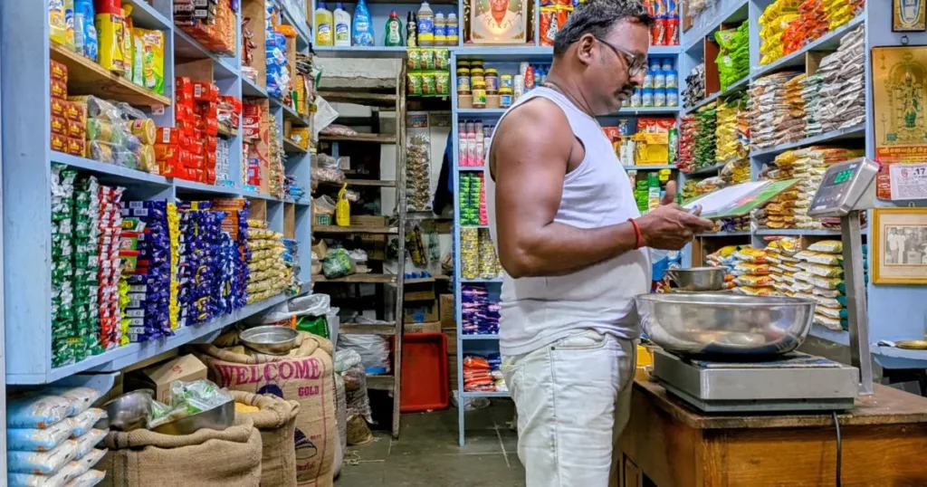 Indian kirana store owner checking stock in his shop