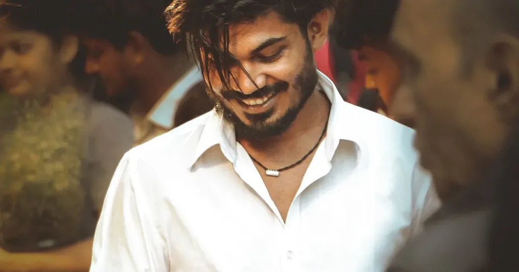A young man in Mumbai smiles while engaging with his smartphone