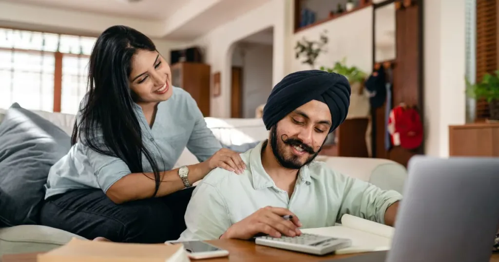 Indian couple reviewing family finances together at home with a laptop