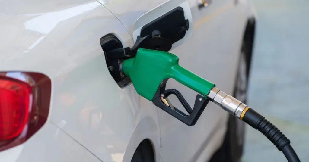 Close-up of a green nozzle refueling a car at a gas station