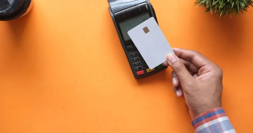Hand holding several credit cards over a desk