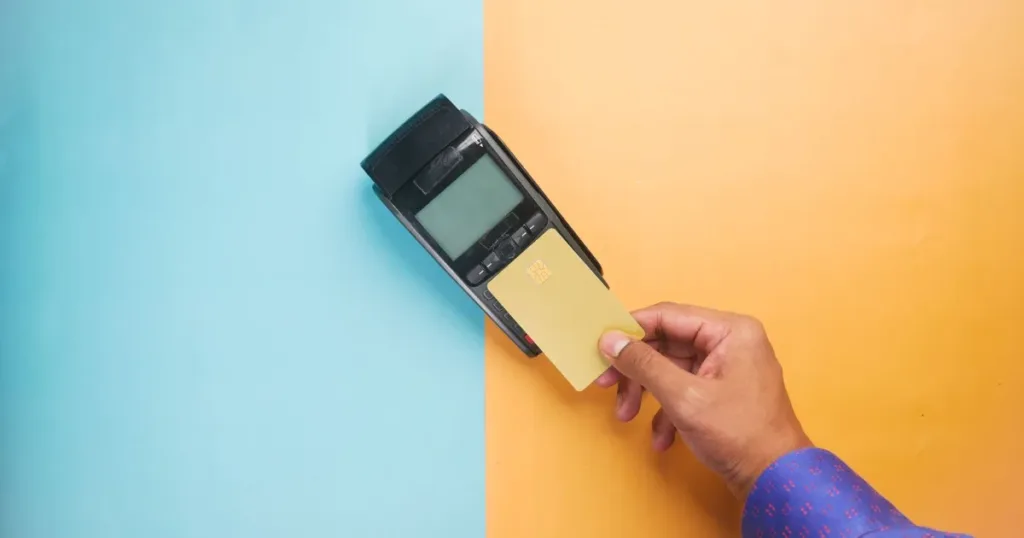 Hand holding a credit card ready to pay, illustrating the IDFC FIRST WOW secured card