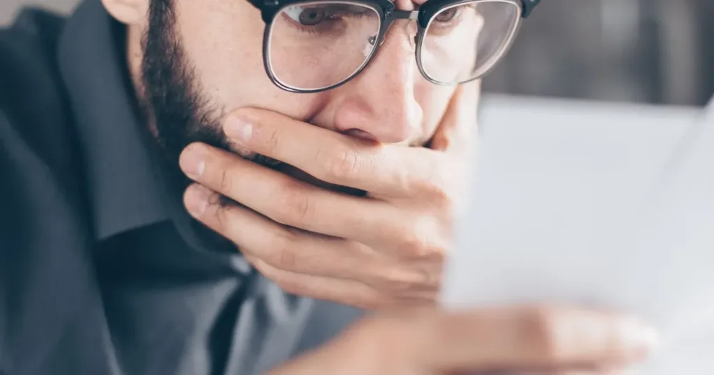 Worried man reviewing financial papers and bills at home