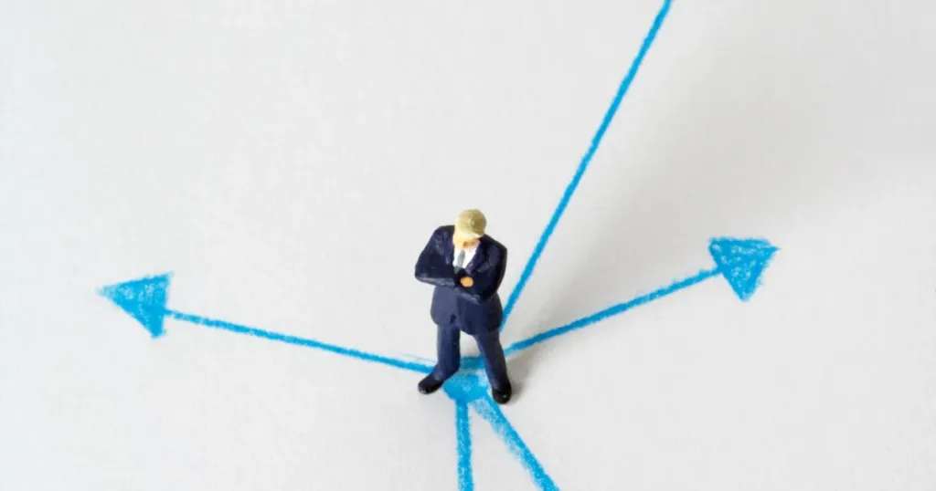 Miniature figure at a crossroads of arrows, symbolizing choosing the right first credit path