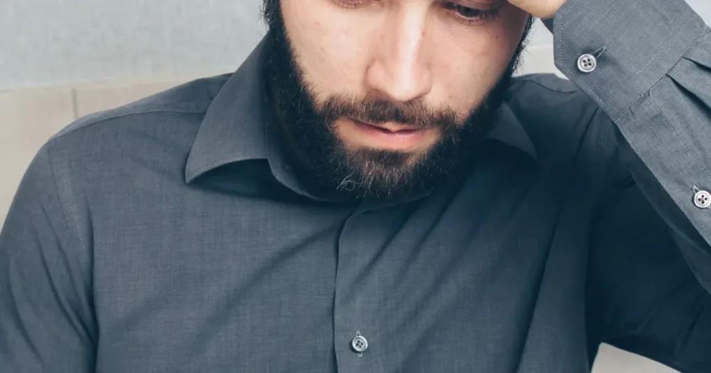 A stressed man looks at his smartphone, holding a credit card