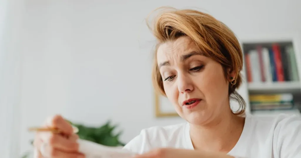 Worried woman reading a rejection letter among bills