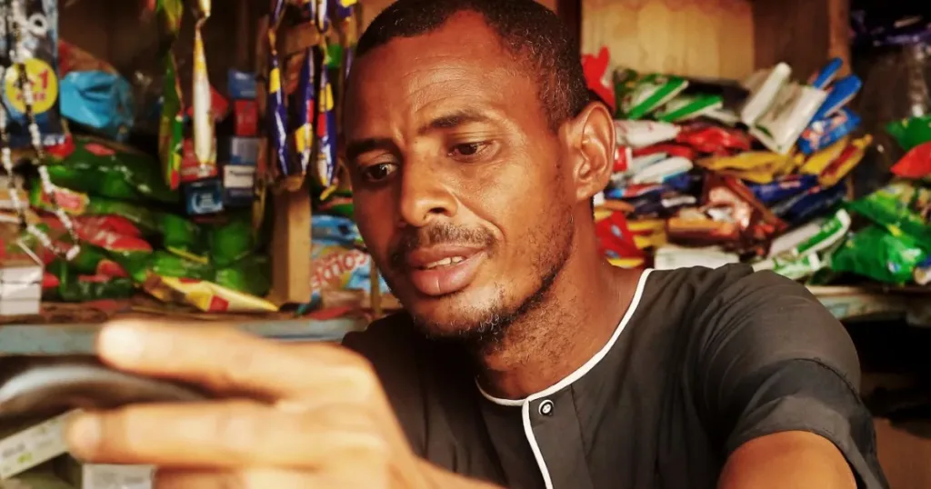 Shop owner arranging inventory on shelves in a small Nigerian store