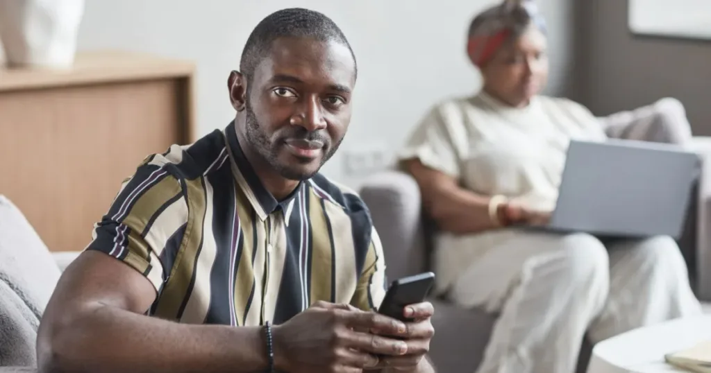 Confident man sitting indoors holding his smartphone, reviewing a digital bank account
