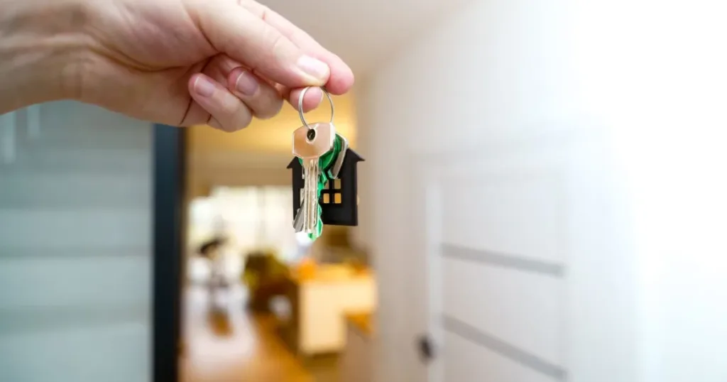 Hand holding house keys inside a modern Lagos apartment