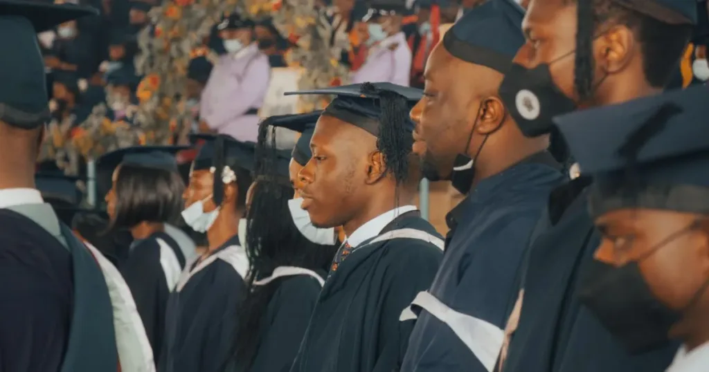 Nigerian university graduates in academic gowns and caps celebrating their achievement