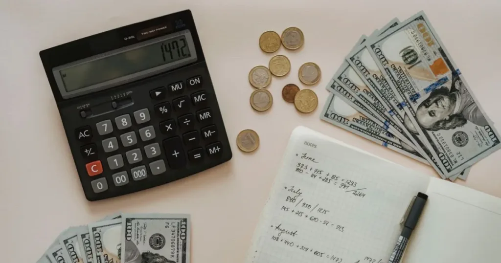 Flat lay of a calculator, cash and coins used for budget planning