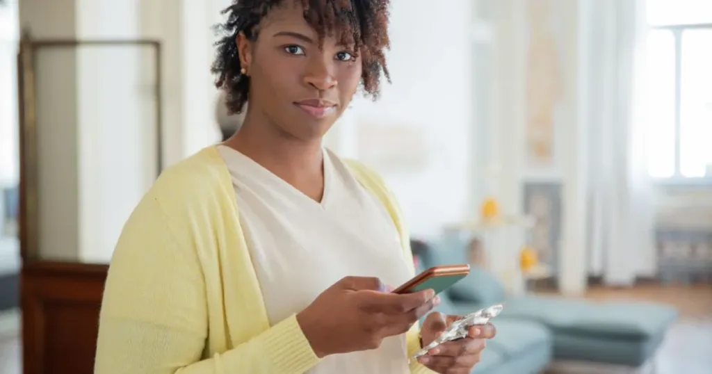 Woman holding her smartphone indoors, checking a mobile wallet app
