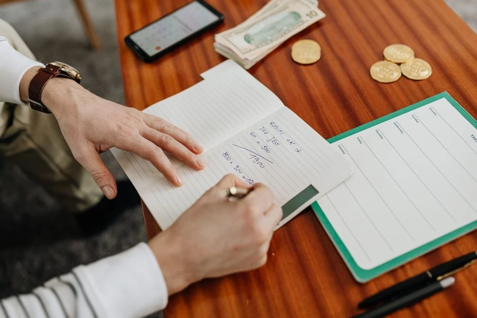 Person writing a budget and repayment plan in a notebook