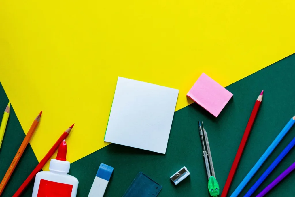 Back-to-school supplies including pencils, glue and notebooks on a colorful table