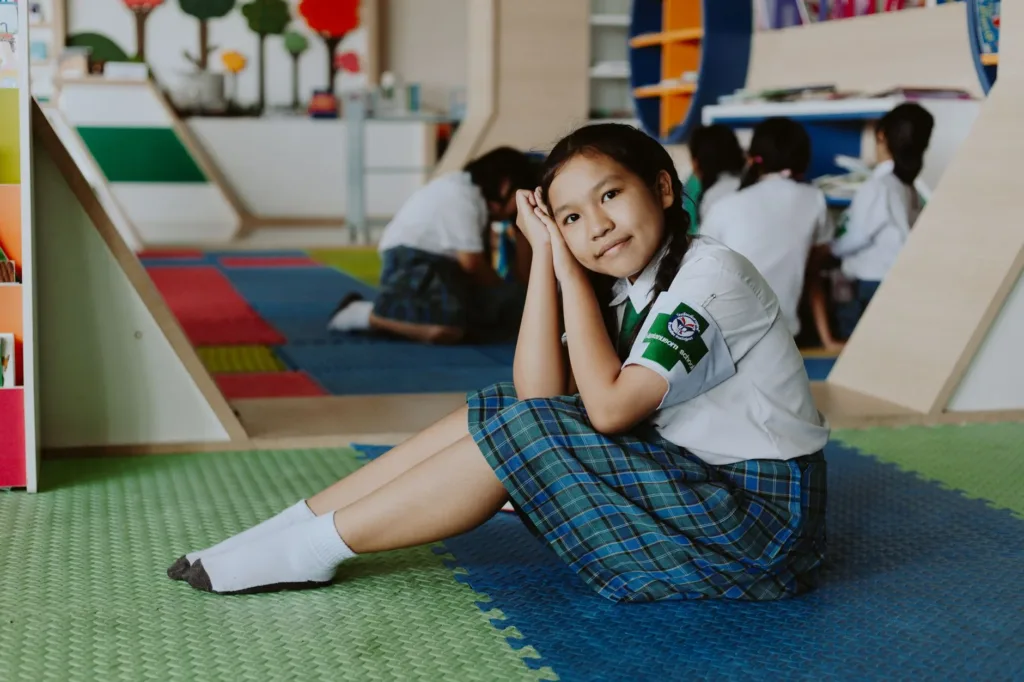 Young student in school uniform sitting on the classroom floor