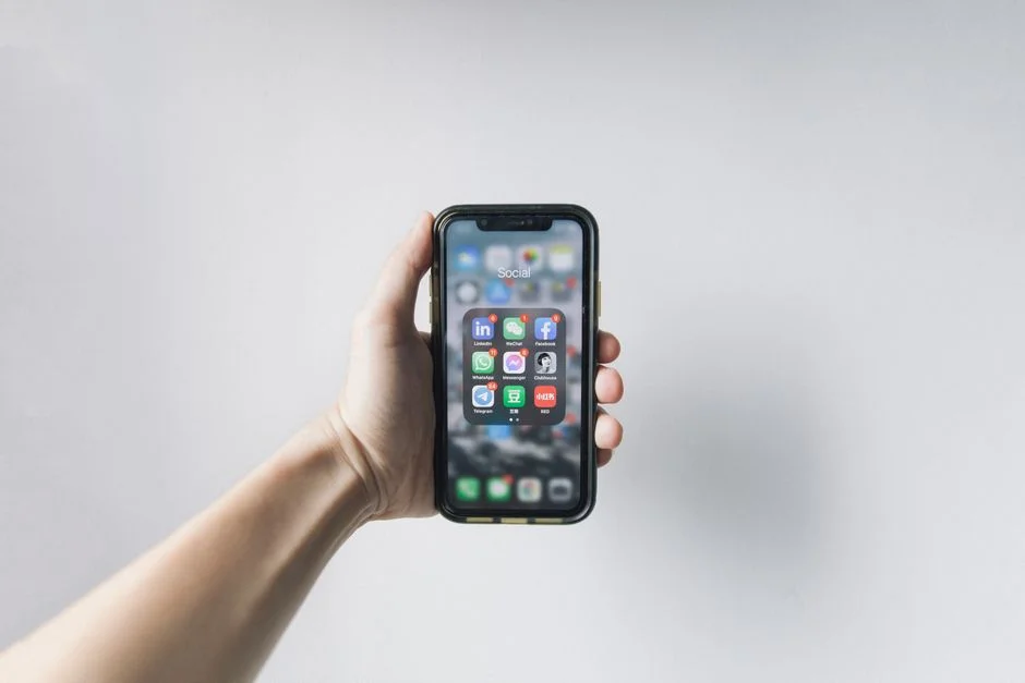 Hand holding a smartphone showing app permissions and home screen icons