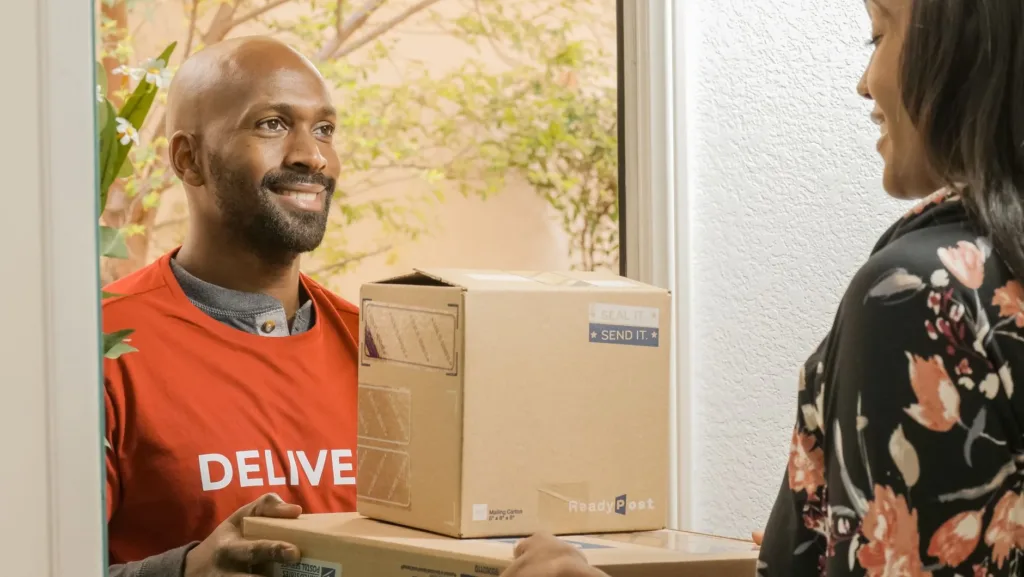 Delivery courier handing a package to a woman at her front door