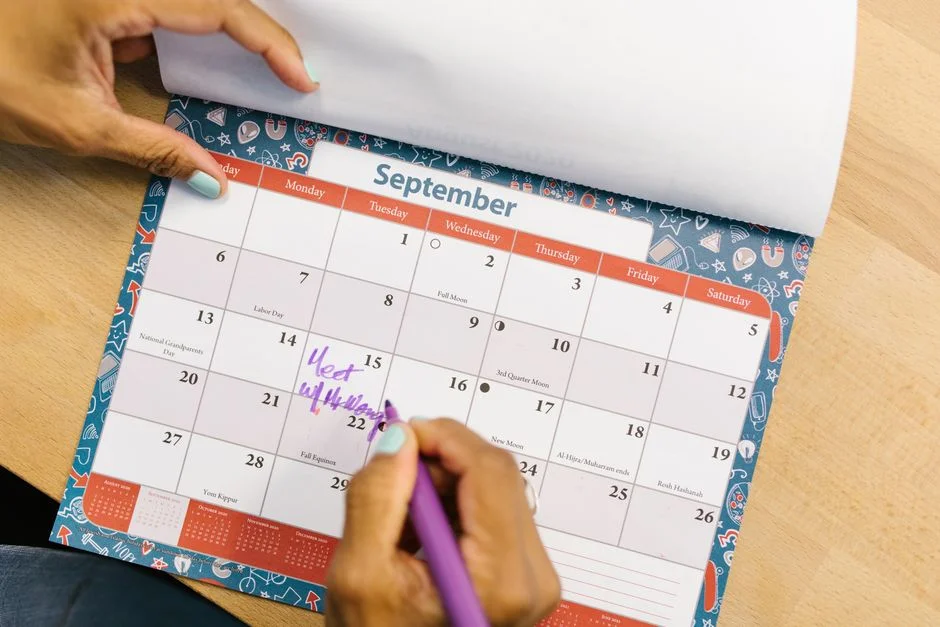 Person marking an important due date on a calendar with a pen