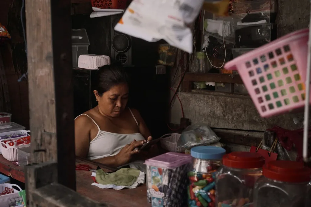 Sari-sari store owner checking a loan option on her phone