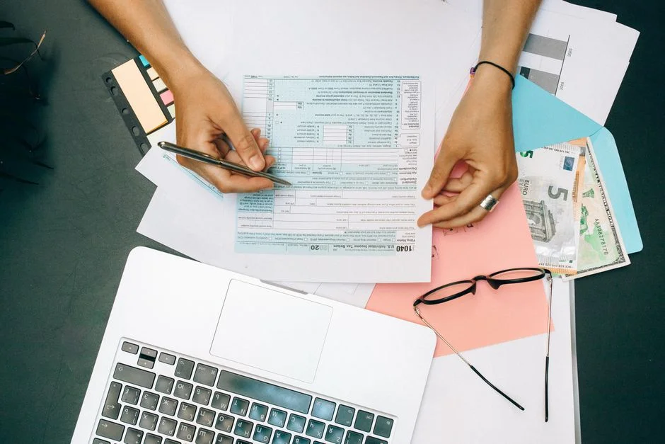 Hands reviewing financial documents next to a laptop, verifying paperwork