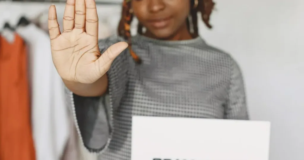 Woman holding up a scam alert warning sign with a stop gesture