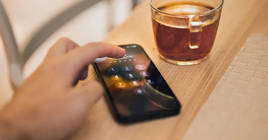Person entering a PIN to unlock a smartphone lock screen, symbolizing mobile account security