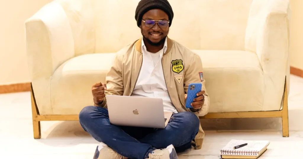 Smiling young professional in Lagos using a laptop and smartphone