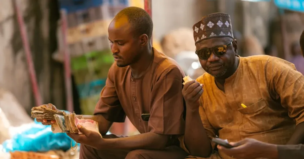 Men counting Nigerian naira banknotes at a street market in Tudun Wada, Nigeria